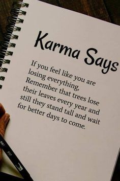 a hand holding a pen over a notebook with the words karma says written on it