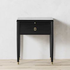 a small black table sitting on top of a wooden floor next to a white wall