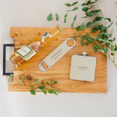 a wooden cutting board topped with bottles of alcohol and a flask