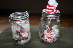 two glass jars filled with candy and snowballs on top of a green table cloth