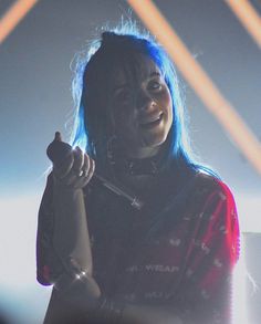 a woman with blue hair and piercings holding a microphone in front of her face