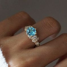 a close up of a person's hand with a blue ring on their finger