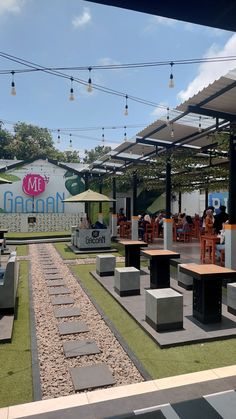 an outdoor seating area with tables and umbrellas on the roof, surrounded by grass