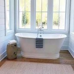 a white bath tub sitting next to two windows