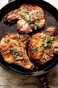 three steaks in a skillet with herbs on top