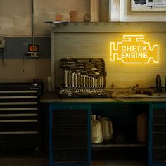 there is a neon sign on the wall next to some workbench drawers and tools