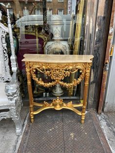 an ornate gold console table in front of a store window