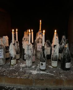 several wine bottles with candles in them sitting on the ground next to some ice and snow