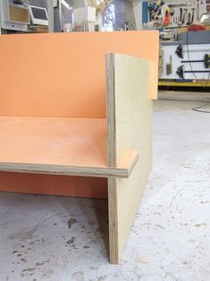 an orange bench sitting on top of a white floor next to a wall and some tools