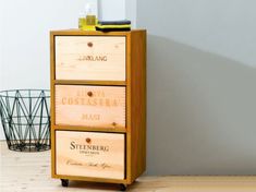 a wooden cabinet with three drawers on wheels in front of a white wall and wood floor