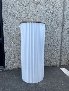 a tall white trash can sitting in front of a building next to a parking lot