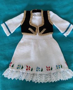 a white and black dress with flowers on the bottom is sitting on a blue blanket