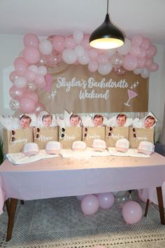 a table topped with pink balloons and pictures on top of it next to a sign