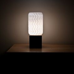 a lamp that is sitting on top of a wooden table next to a dark wall