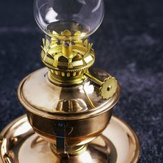 a gold plated clock with a glass dome sitting on it's stand, in front of a dark background