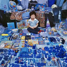 a young boy sitting on the floor surrounded by blue items