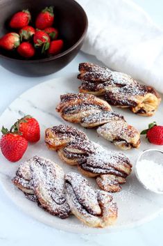 powdered sugar covered pastries on a plate with strawberries