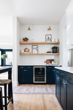 a kitchen with blue cabinets and white walls, wood flooring and open shelving