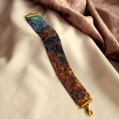 a beaded bracelet laying on top of a white bed next to a pink pillow