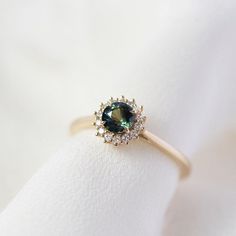 a close up view of a ring on a white cloth with a green stone in the center