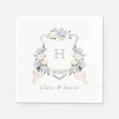 a white square paper napkin with blue flowers and ribbon on the front, in an ornate frame