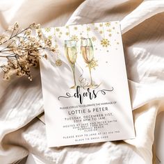 two glasses of champagne on top of a white sheet next to some baby's breath flowers