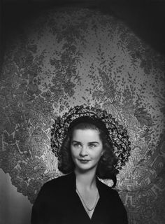 an old black and white photo of a woman in front of a wallpapered background