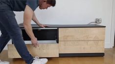 a man standing next to a tv on top of a wooden cabinet