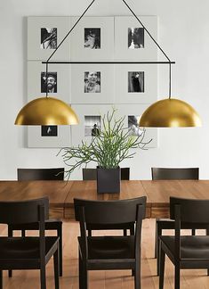 a dining room table and chairs with pictures on the wall above it, along with a potted plant