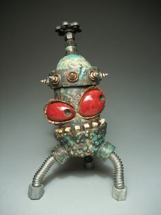 an odd looking object with red eyes and metal parts on it's head, sitting in front of a gray background