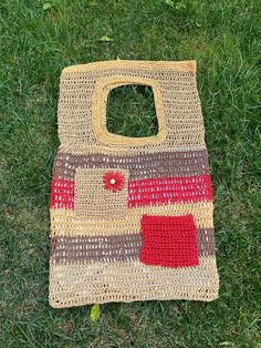 a crocheted bag laying on the ground with grass in front of it,