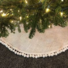 a close up of a christmas tree skirt on the ground with lights in the background