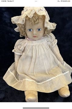 an old fashioned doll with blue eyes wearing a white dress and bonnet on it's head