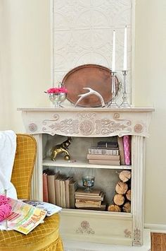 a white shelf with books and candles on top of it next to a yellow chair