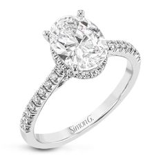 a white gold engagement ring with an oval cut diamond center and pave set shoulders