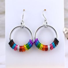 a pair of hoop earrings with multi colored beads on each earring, sitting on top of a white surface