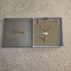 the disney necklace is in its box on the carpet