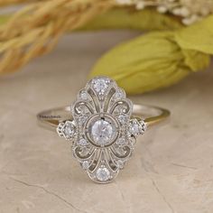 a diamond ring sitting on top of a table next to some dried flowers and leaves