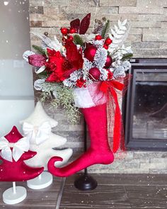 a christmas stocking with flowers in it next to a fireplace