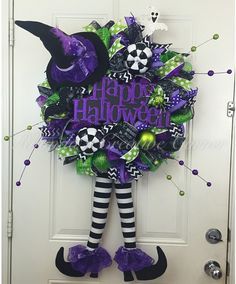 a wreath that says happy halloween hanging on the front door with witch legs and boots