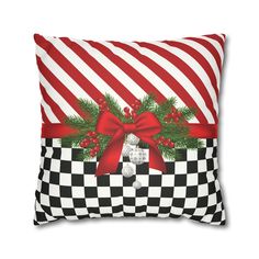 a christmas pillow with a red bow and holly wreath on the front, black and white checkerboard background