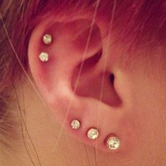 a close up of a person's ear with three piercings