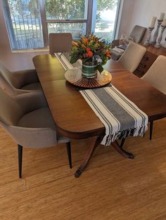 a dining room table and chairs in front of a large window with flowers on it