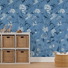 a blue floral wallpaper with white flowers and giraffes on the side