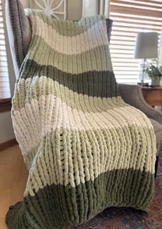 a green and white blanket sitting on top of a chair