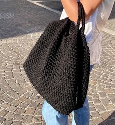 a woman carrying a black crocheted bag on the street