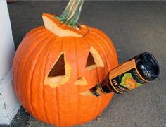 a carved pumpkin sitting next to a wall with a beer bottle in it's mouth