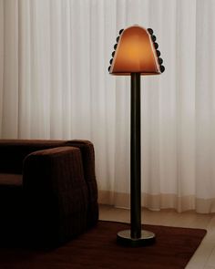 a lamp that is sitting on top of a table in front of a chair and window