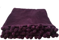 a purple blanket with pom - poms on the top and bottom, folded up