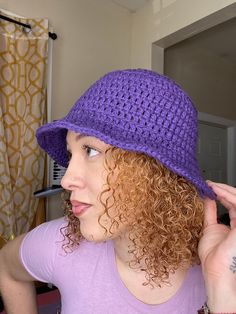 a woman with curly hair wearing a purple hat